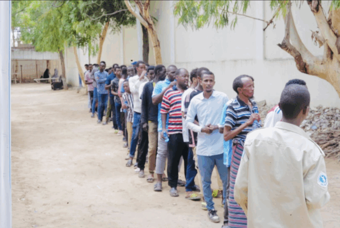 A policeman is seen standing in front of a group of people who reportedly came for voter registration in Mogadishu on 28 May 2025. | PHOTO/Private.