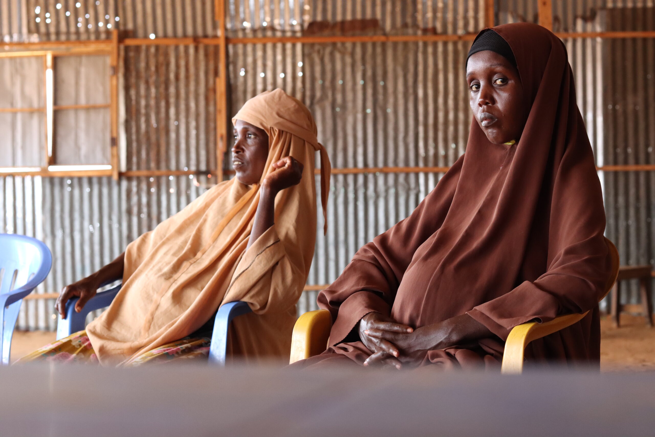 Two displaced women sit as they wait for an interview with the SJS Baraarug team outside Mogadishu, Somalia, in June 2025. PHOTO: Abdullahi Mohamed Ali.